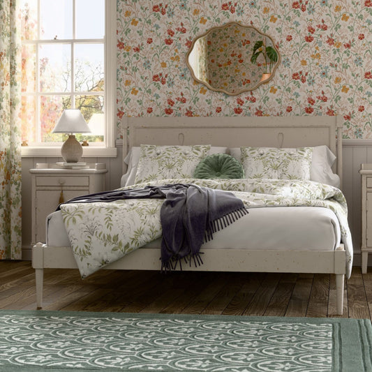 Bedroom with floral wallpaper, bed with green and white bedding, and nightstands.