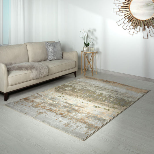 A modern abstract design area rug with metallic gold accents, styled on the floor in front of a sofa and side table with a large decorative gold round mirror on a white wall.