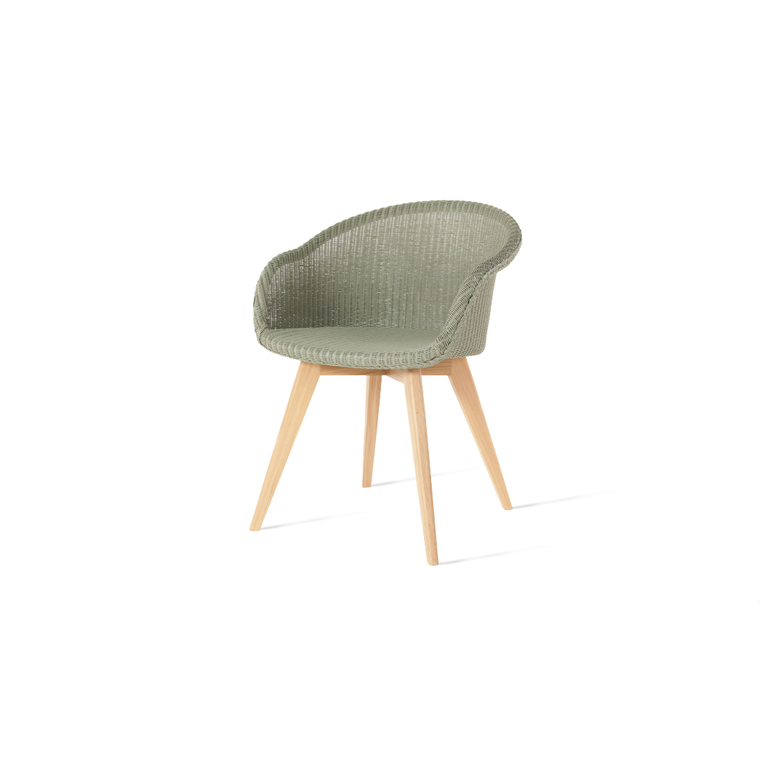 A dining chair with a green Lloyd Loom weave seat and an oak wood base.
