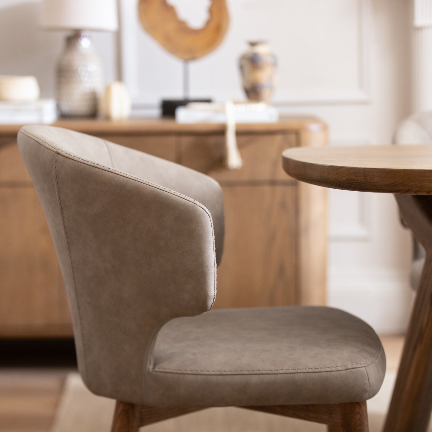 Beige chair in a room with wooden furniture and decor