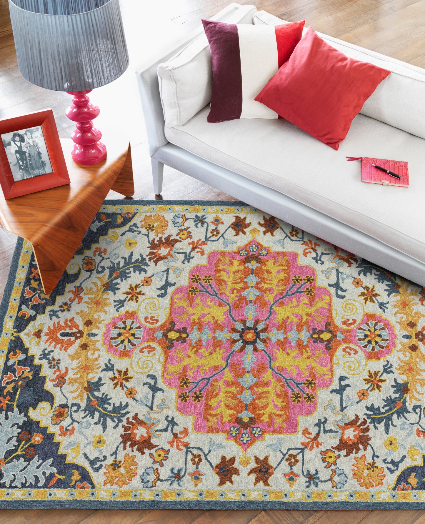 A multicolored wool rug with a distinctive Persian medallion design, placed on a floor in a room with a white sofa, showcasing its vibrant colors.