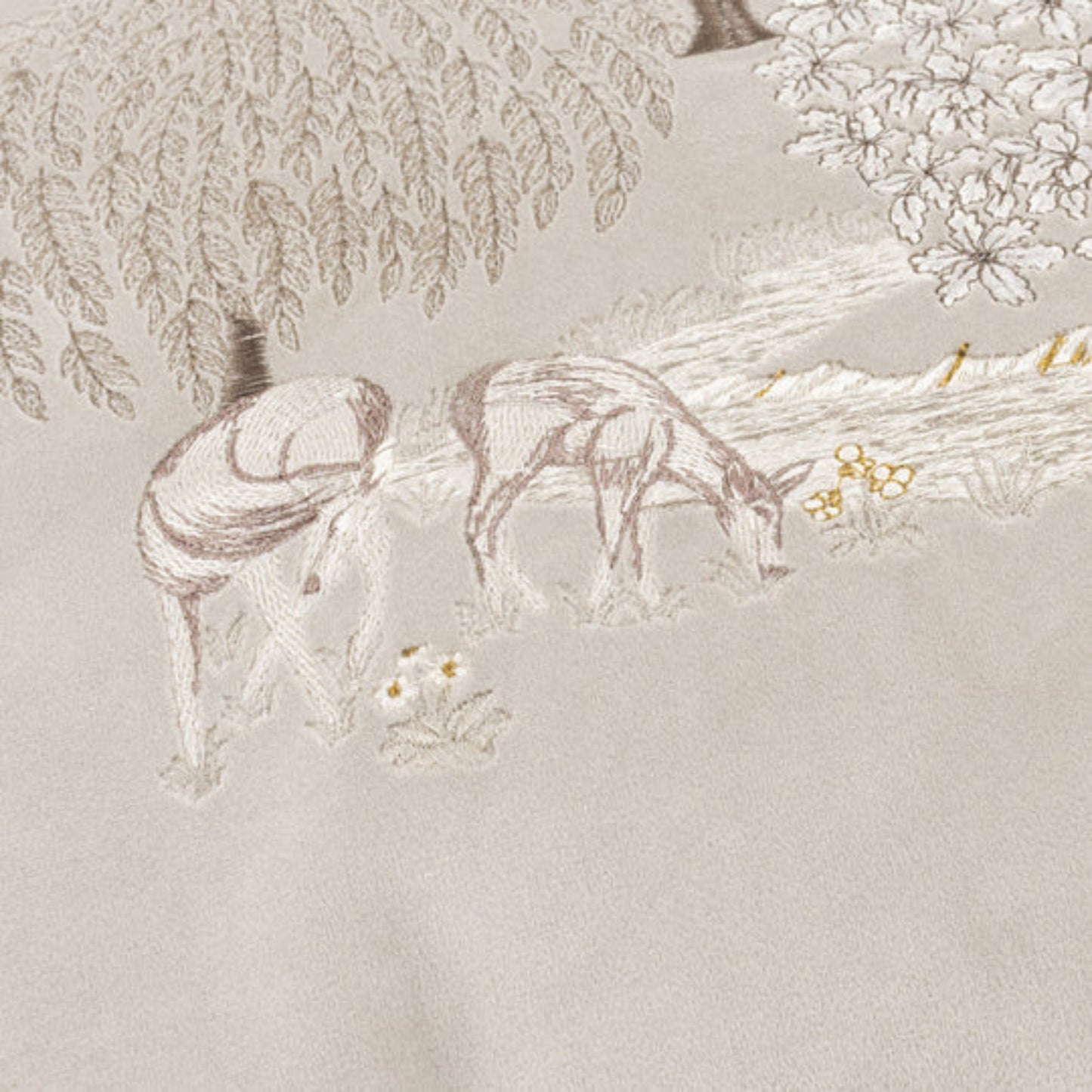 Embroidered fabric with a deer and floral design on a neutral background