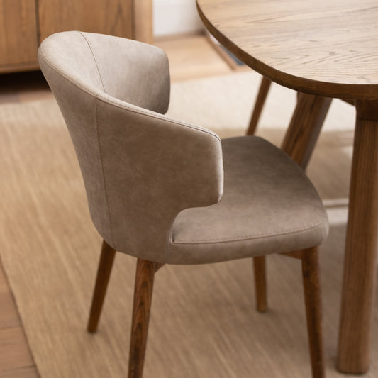 Beige chair with wooden legs in a room with a wooden floor and table.