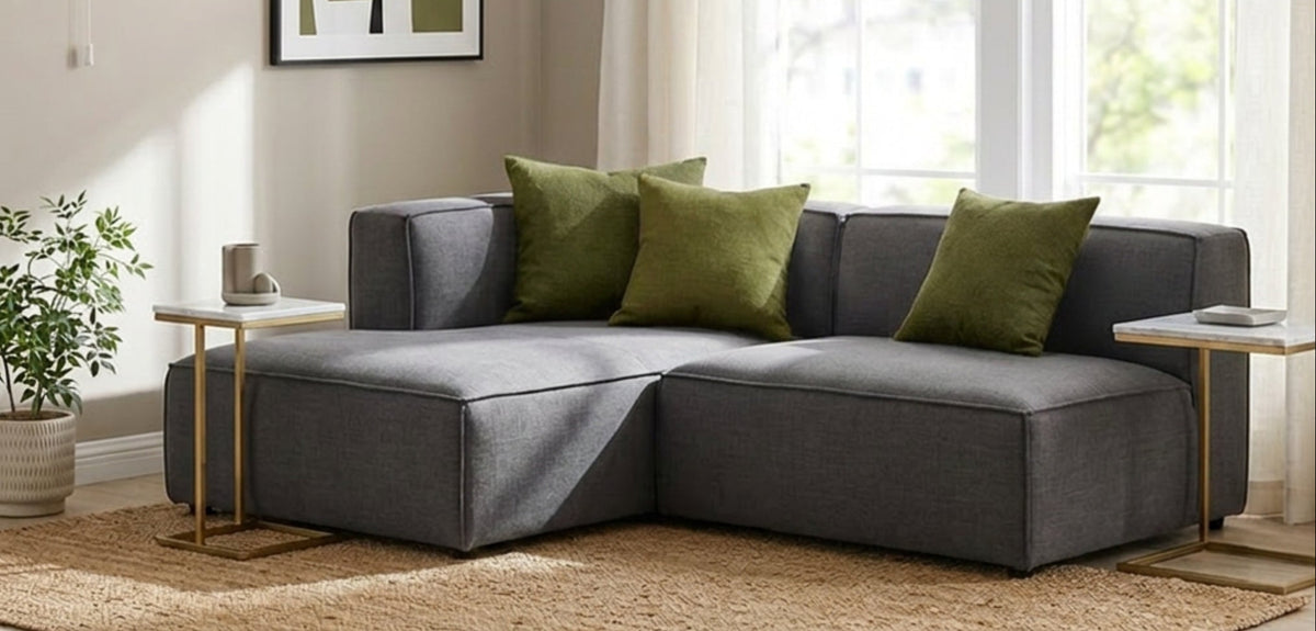 Modern living room with gray sectional sofa, green cushions, and a chandelier.