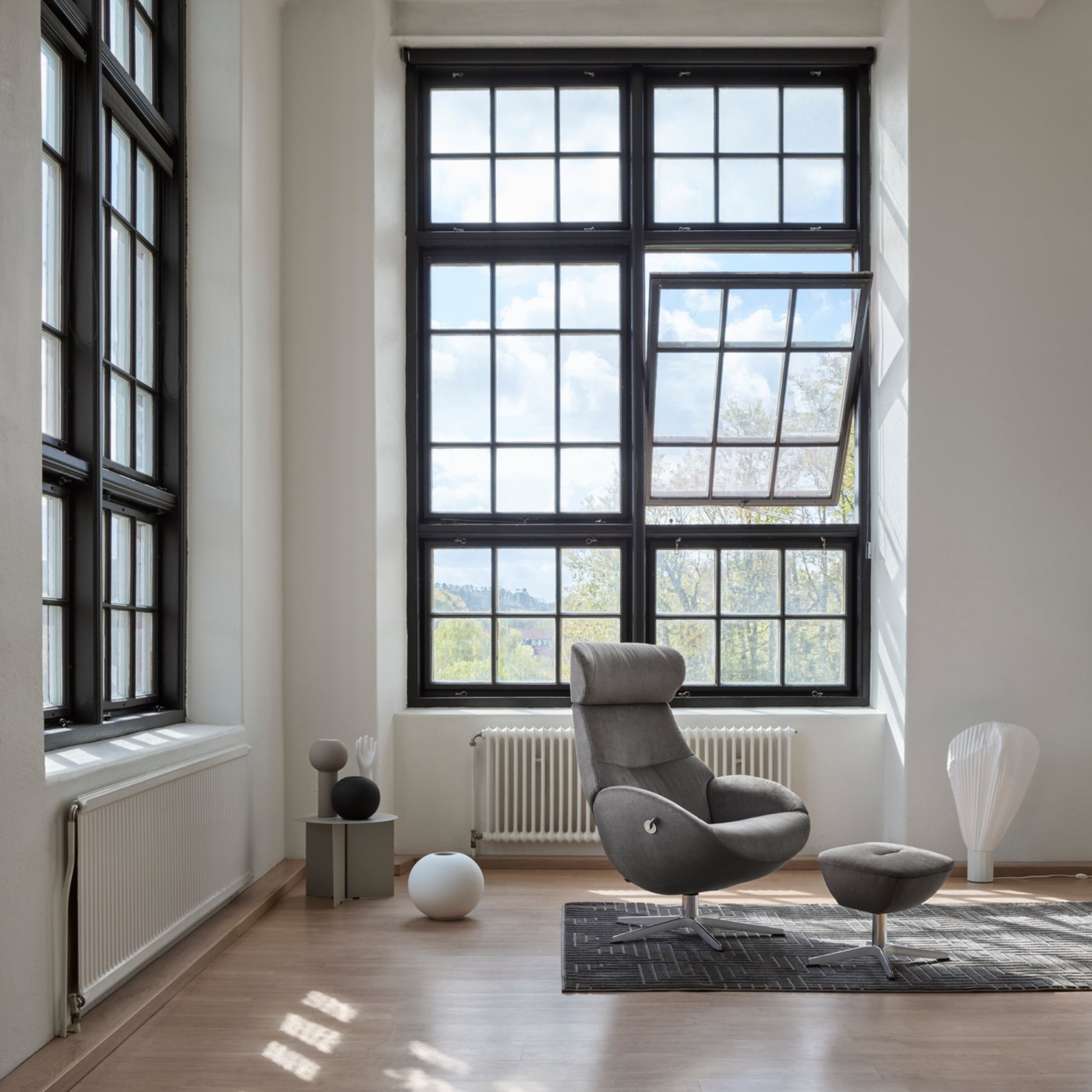 Modern living room with a grey armchair and large windows.