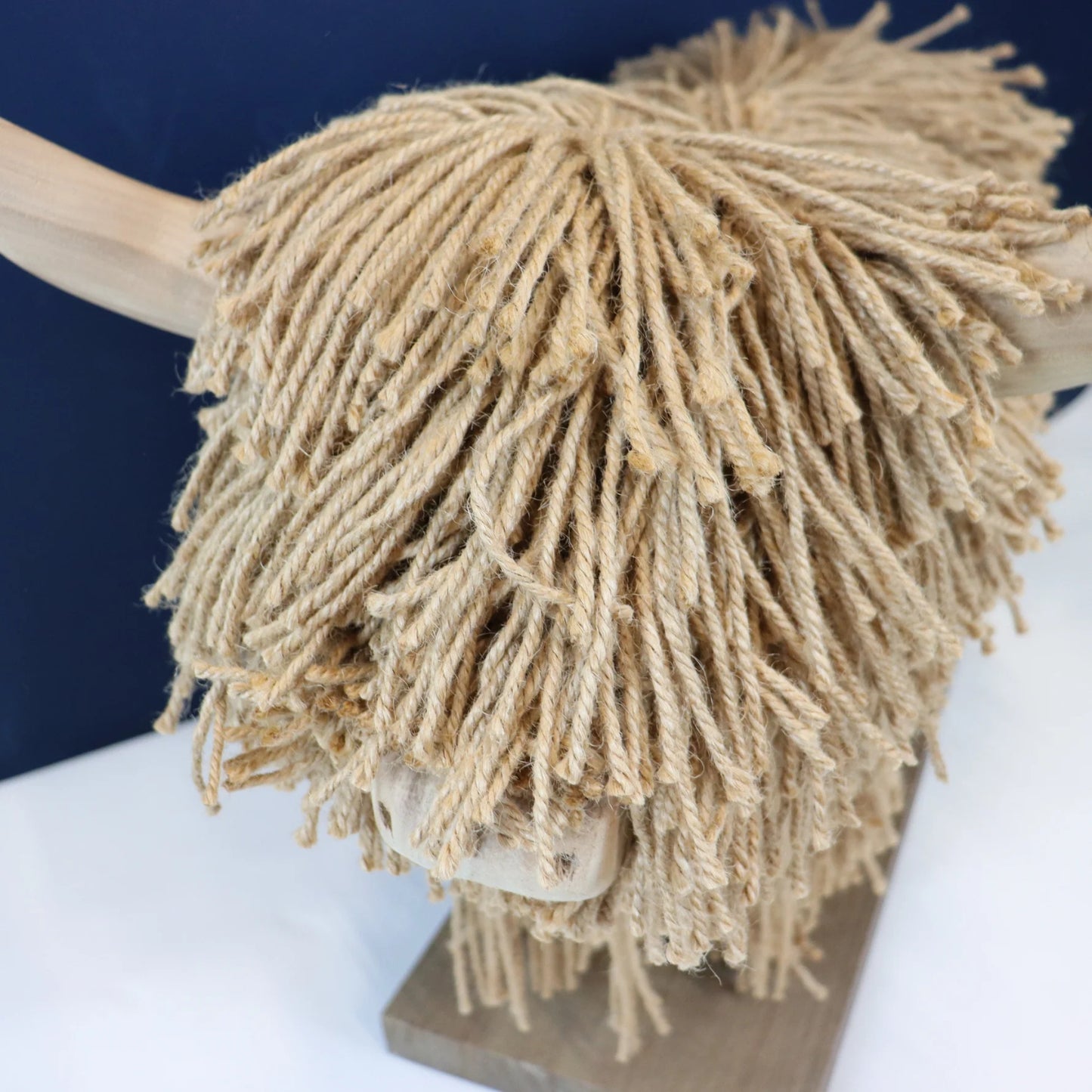 Close-up of a jute highland cow head on a white surface with a blue background