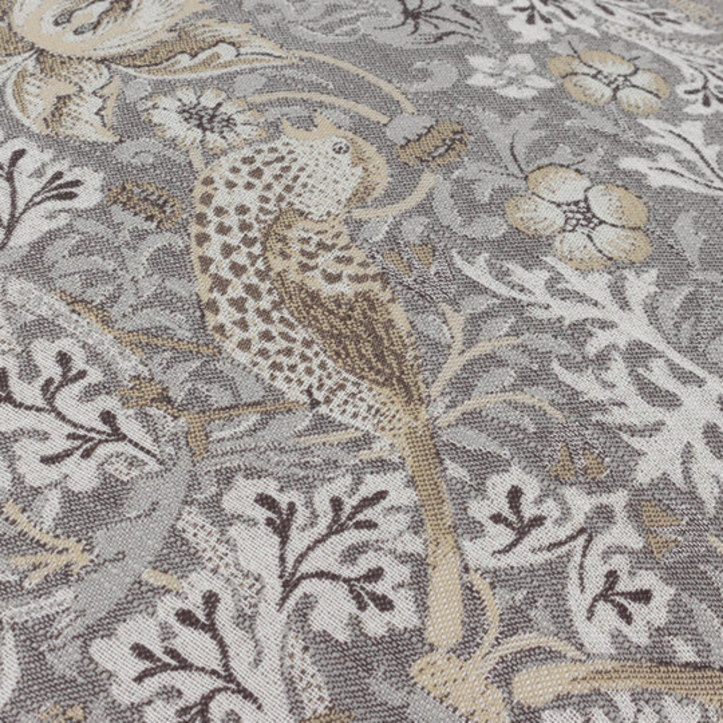 Close-up of a fabric with a bird and floral pattern on a gray background