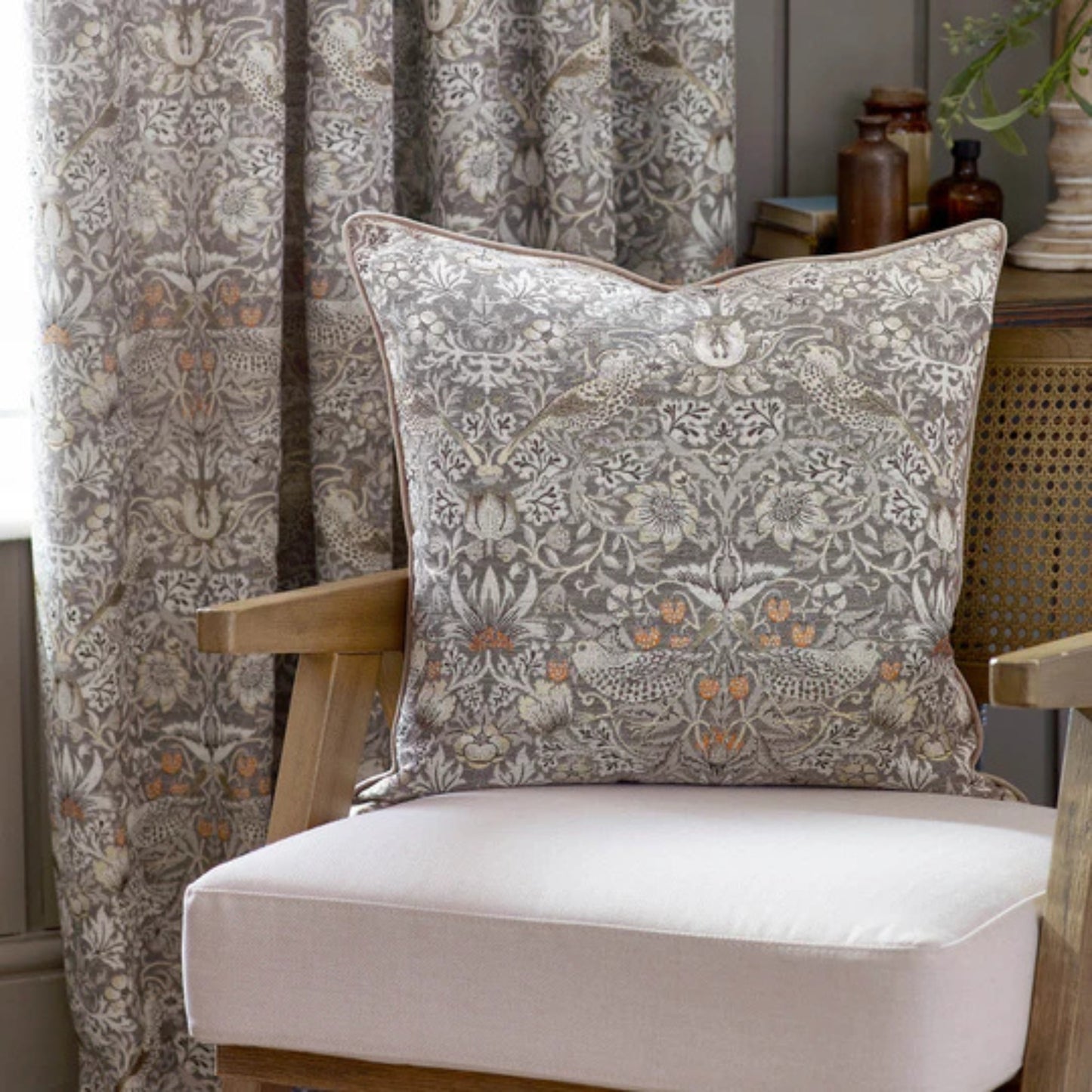 Decorative pillow with floral pattern on a chair next to patterned curtains