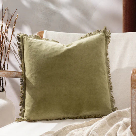 Green pillow with fringes on a white sofa