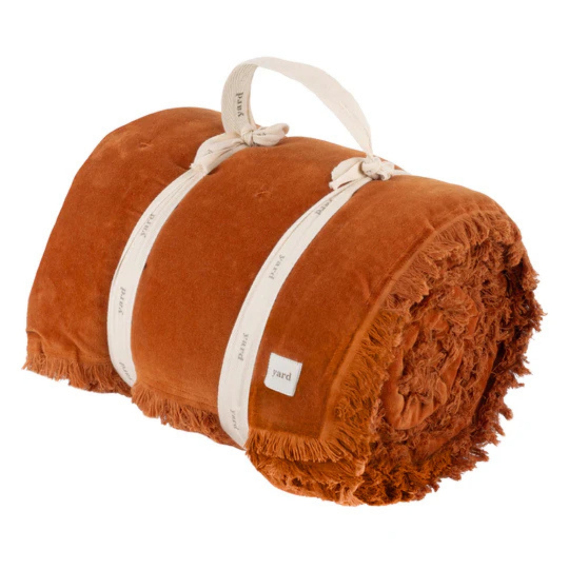 rolled up rust throw tied with white cotton ribbon on a white background