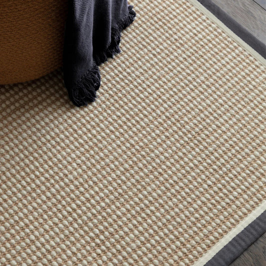 Close-up of a textured beige rug with a dark border