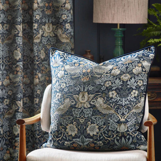 Navy floral and bird patterned cushion sitting on an accent chair in a living room setting