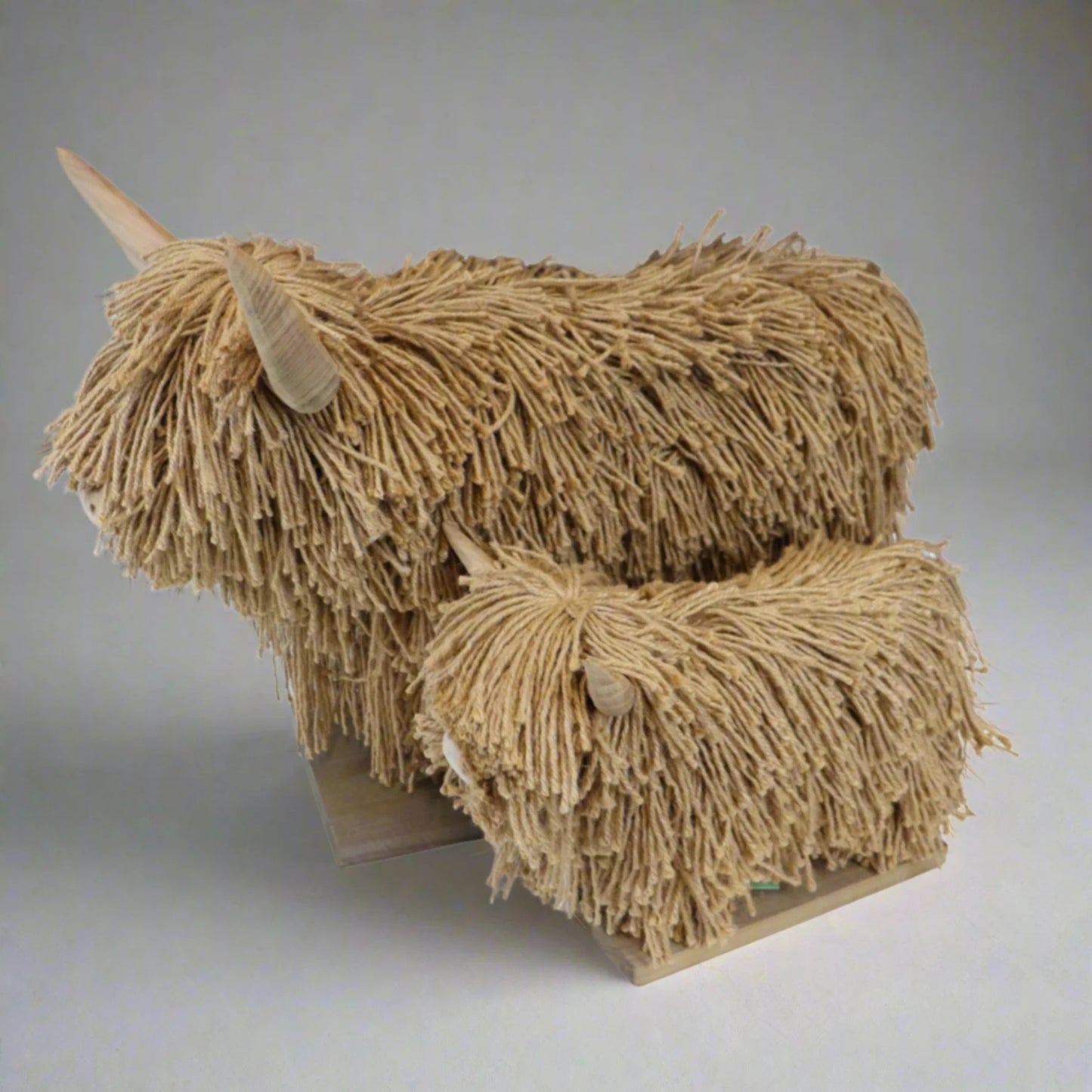 Jute sculptures of a highland cow with textured fur effect on a plain background