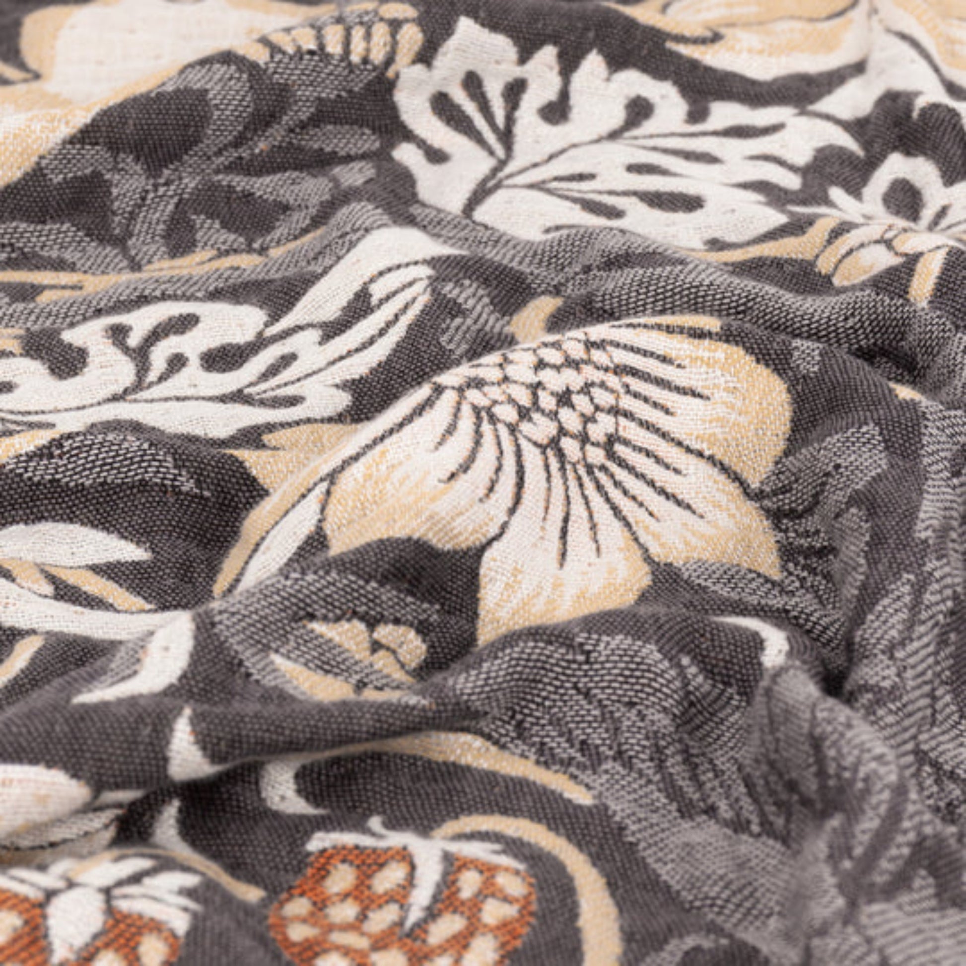 Open throw featuring a floral and bird pattern in biscuit tones on a dark fabric background