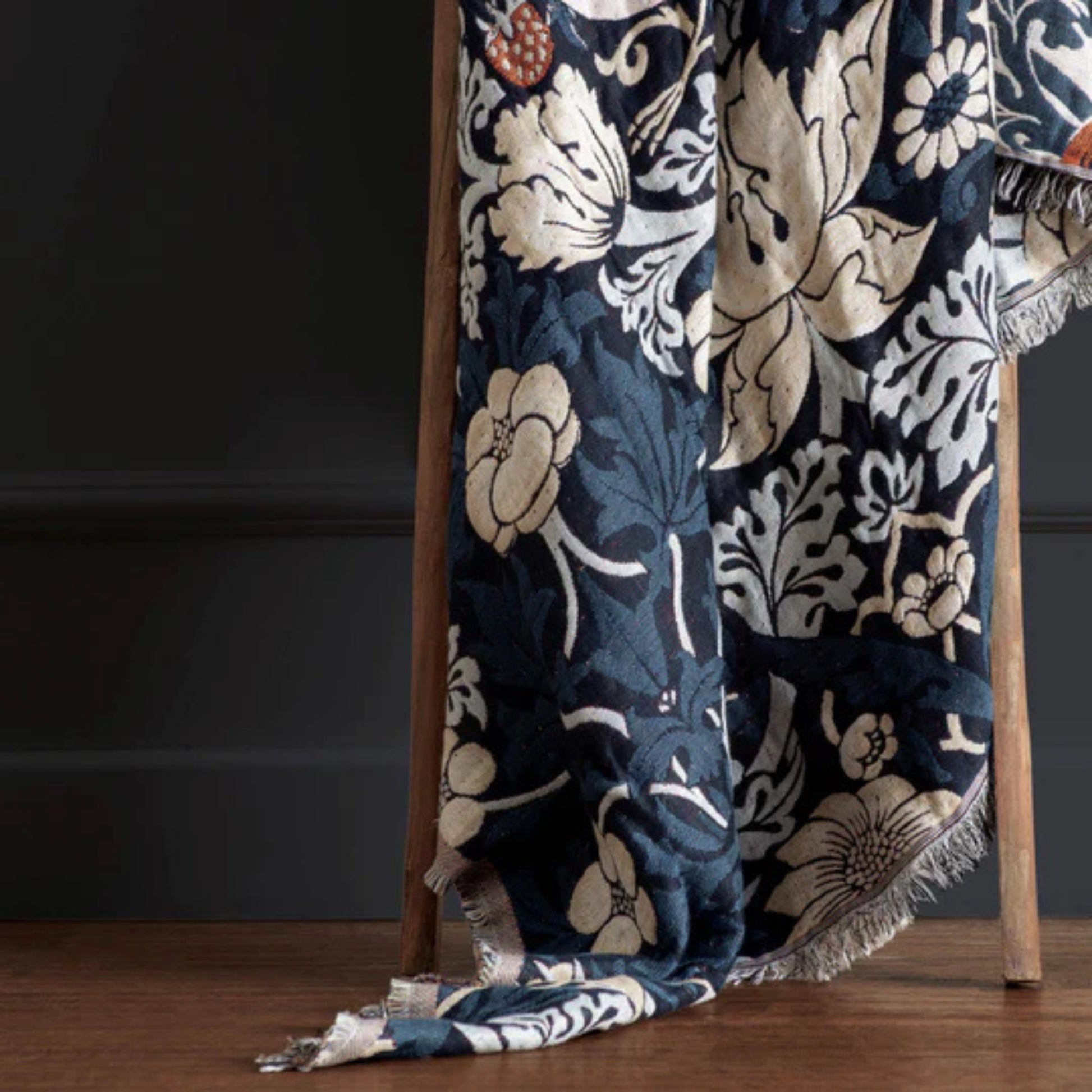 Floral patterned throw blanket draped over a chair against a dark background