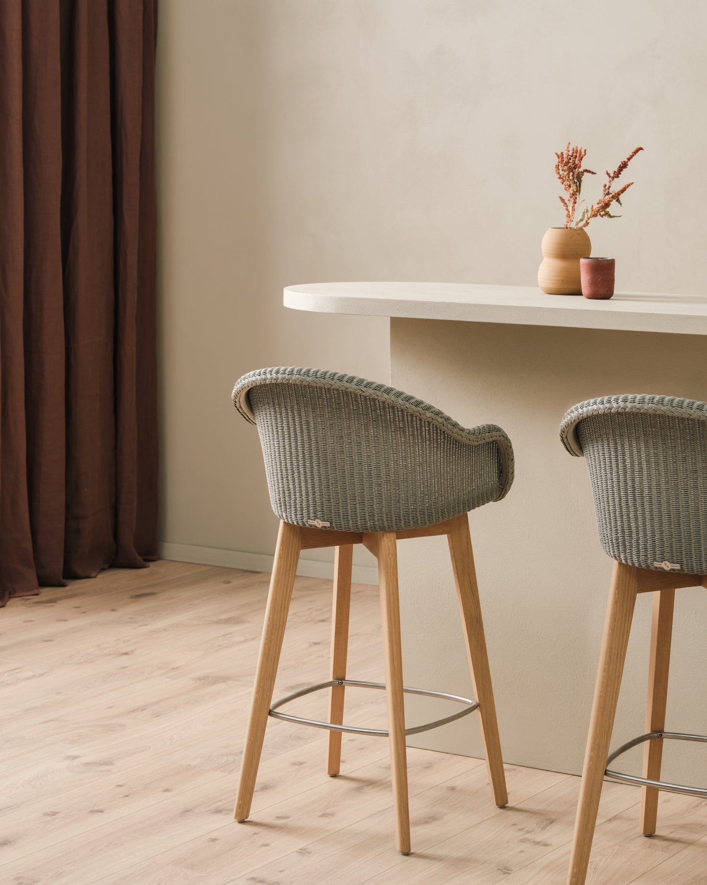 Light Pebble counter stools in delicate Lloyd Loom weave with a beautifully crafted oak wood base, sitting at a kitchen bench on a light toned wood floor.