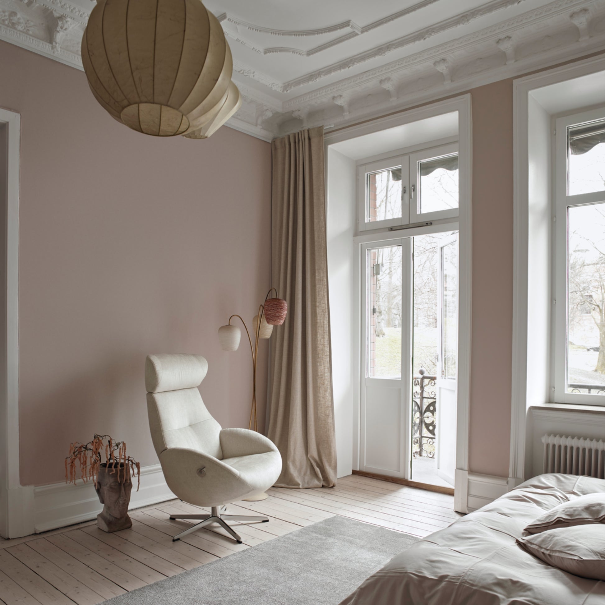 A white Globe Recliner Egg Chair with a footstool in a room with pink walls, a large window, and a decorative ceiling.