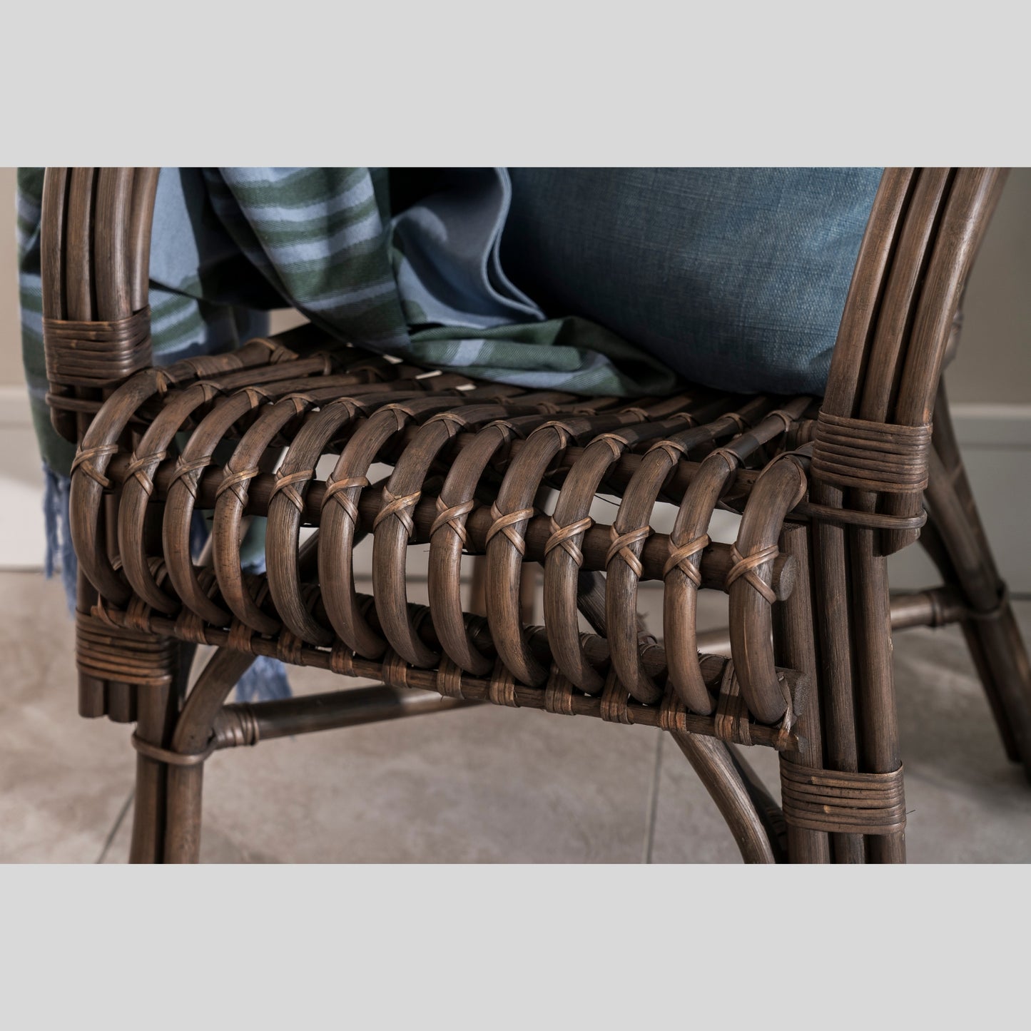Close-up of a wicker chair with a person sitting on it, blurred background