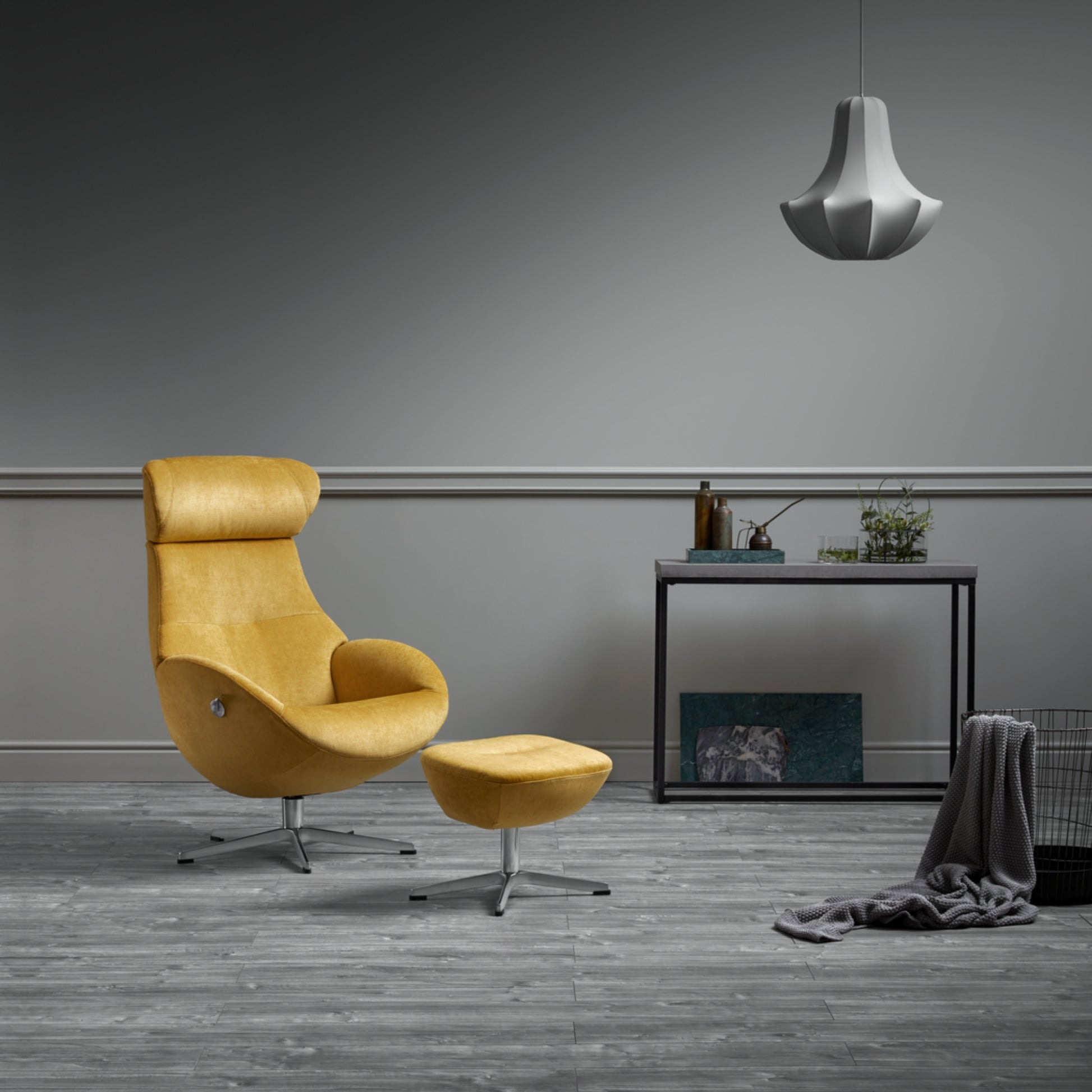 Yellow armchair and foot stool in a modern room with a grey wall and wooden floor.