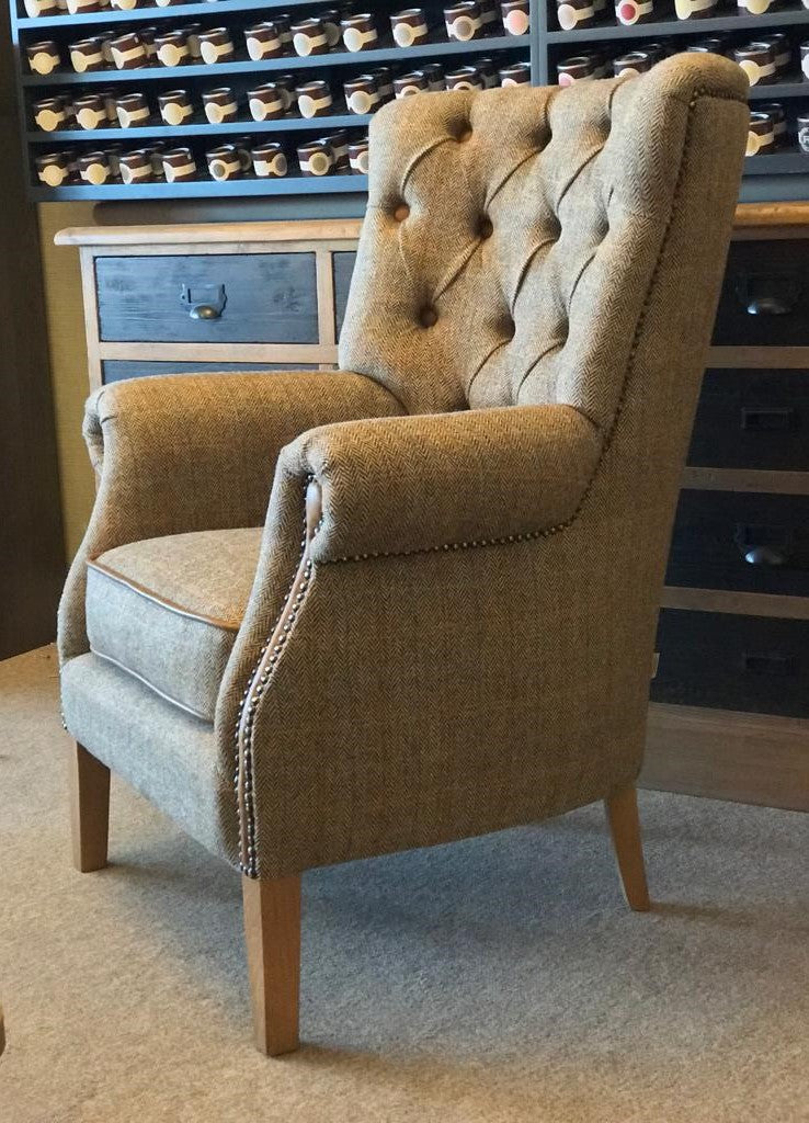 A classic armchair with gently curving arms and deep buttoning, upholstered in brown Harris Tweed fabric.