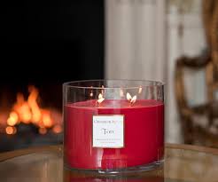 Re lit large round candle in a glass container on a tablke in front of an open fire