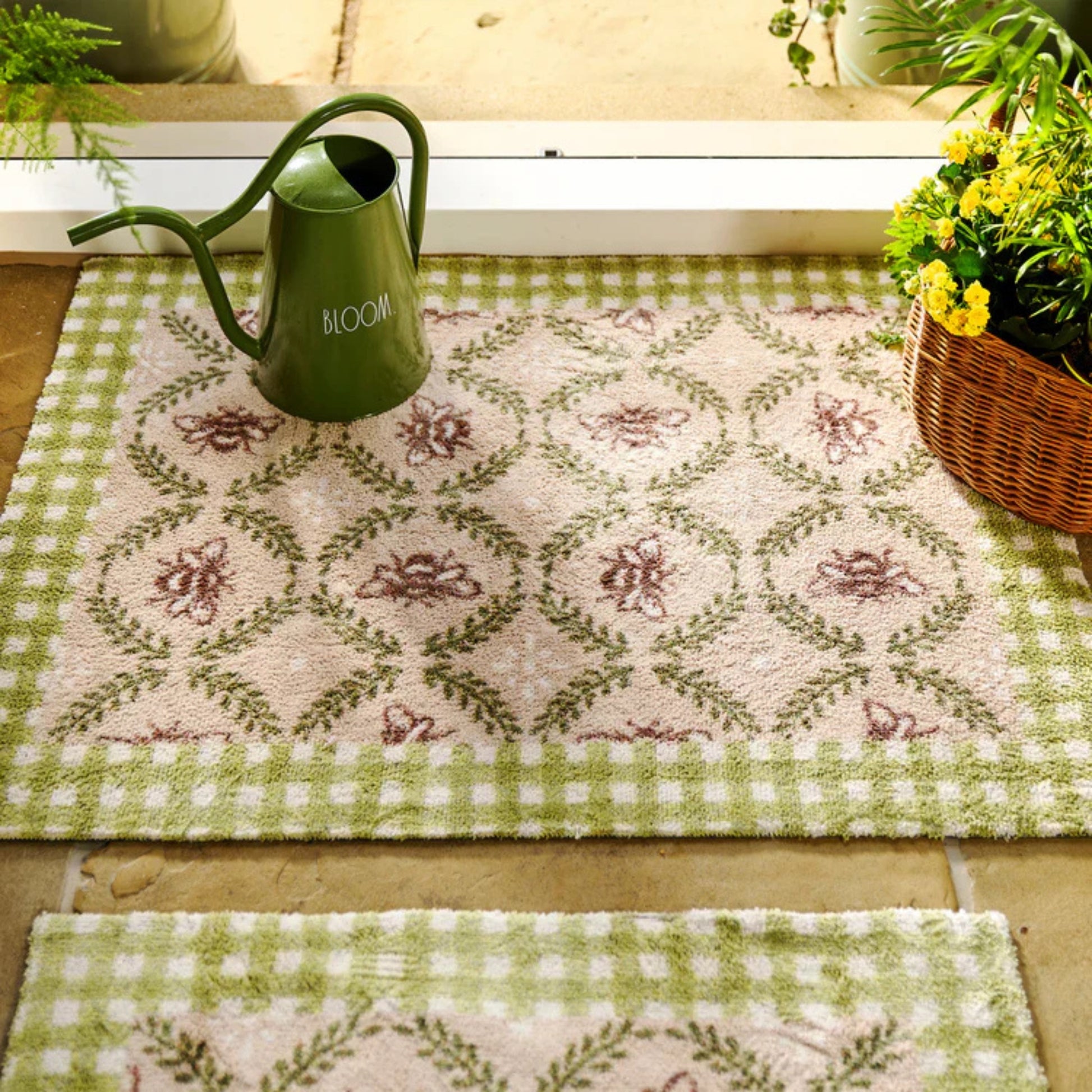 Decorative green and white checkered rug with floral patterns, a green watering can, and plants.