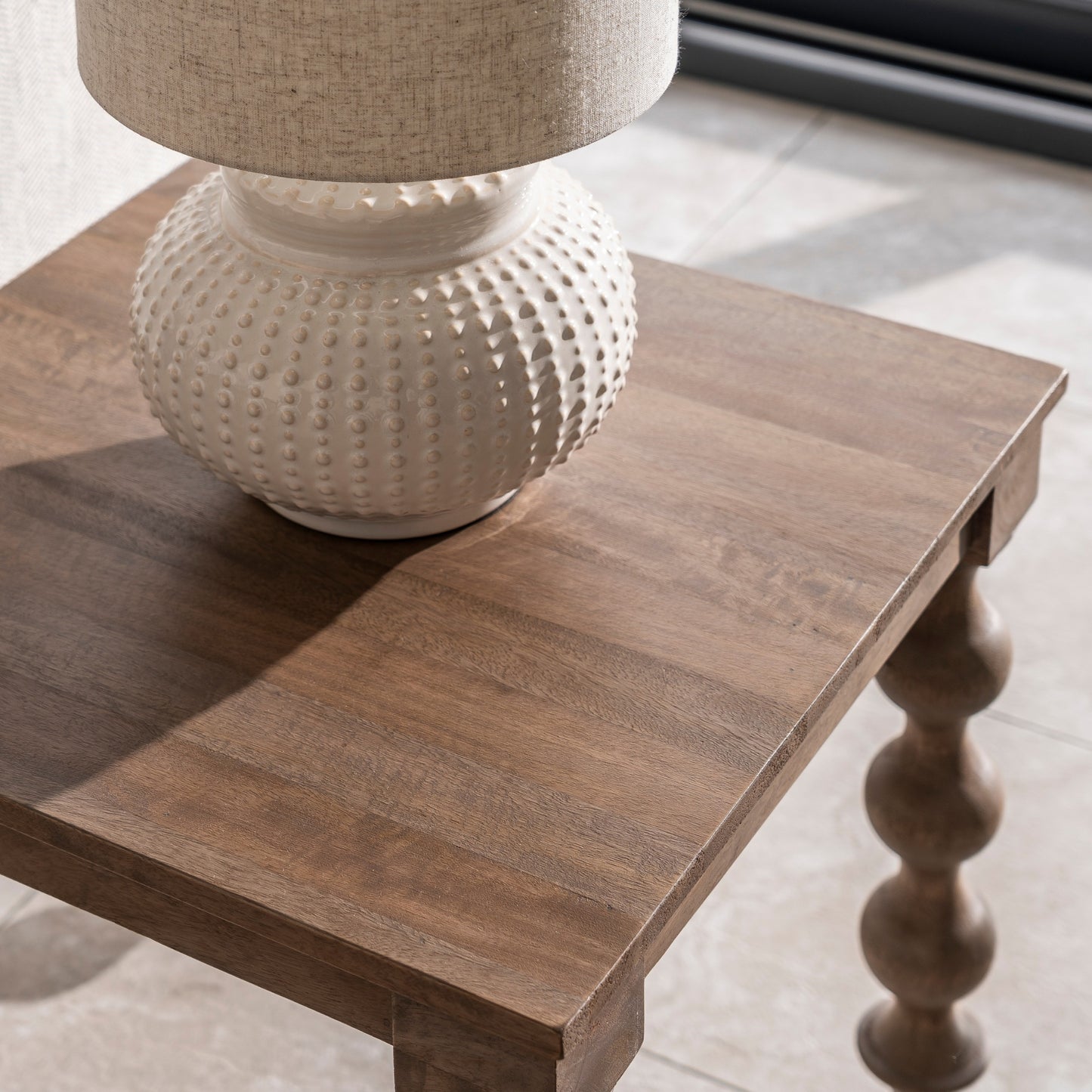 Wooden table with a textured white lamp on top