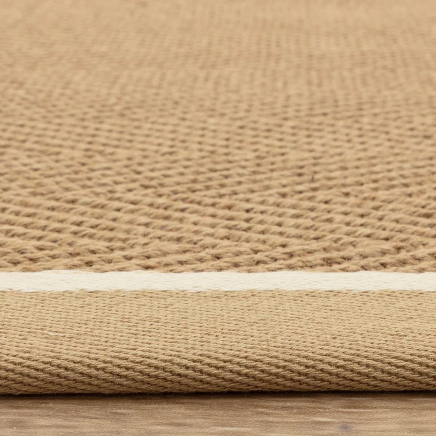 Close-up of a beige woven rug on a wooden floor