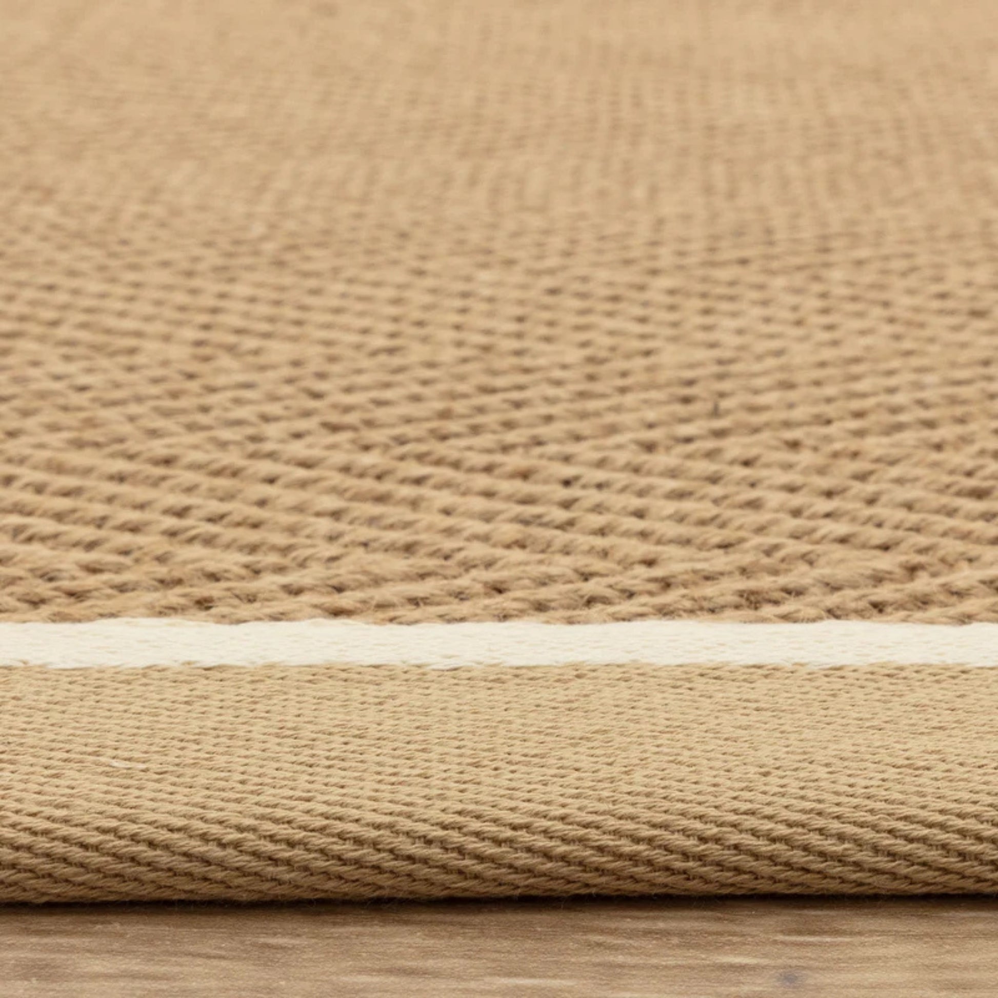 Close-up of a beige woven rug on a wooden floor