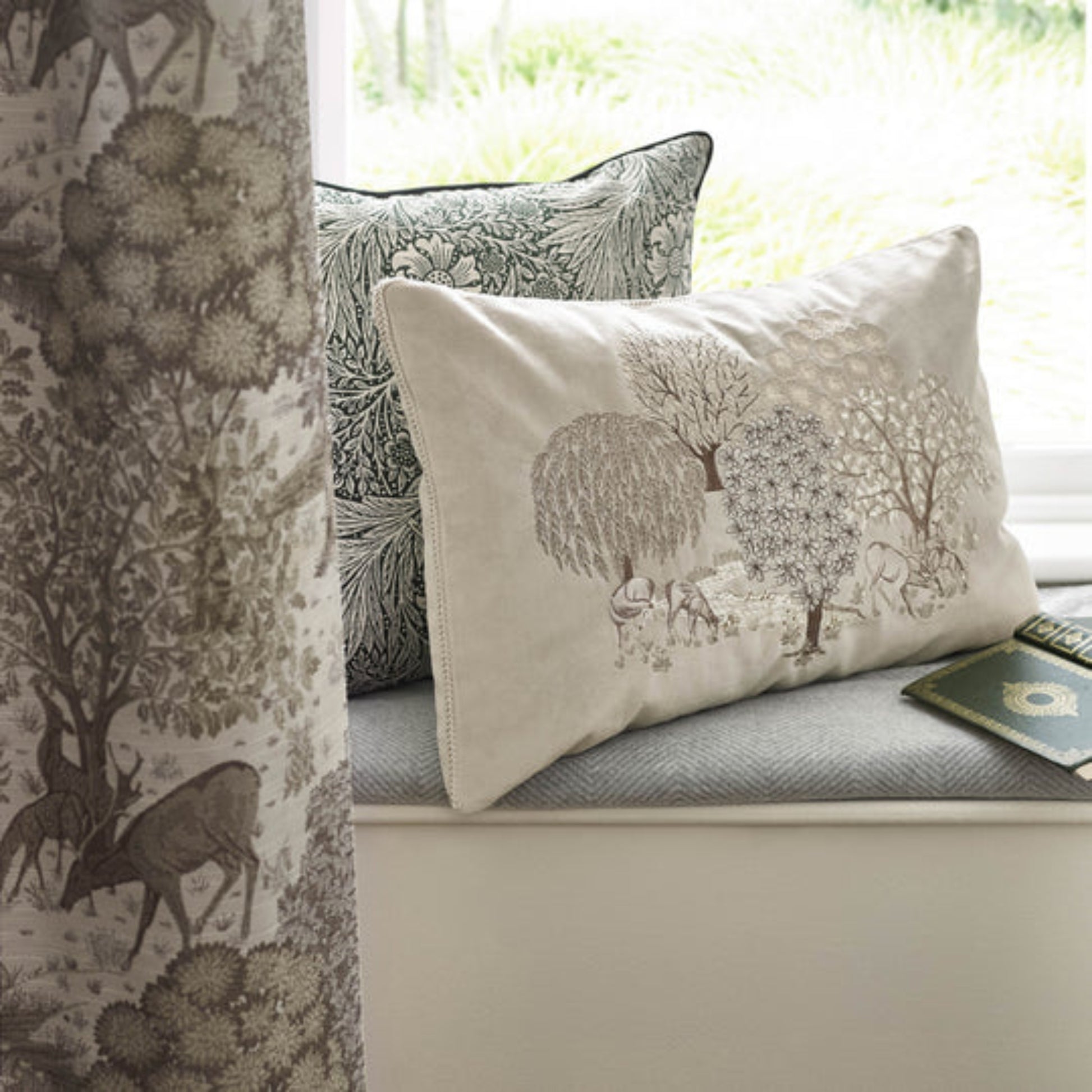 Decorative pillows with nature-themed patterns on a window seat.