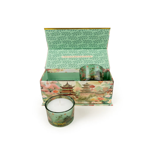 Decorative candle in a matching box with a scenic design on a white background