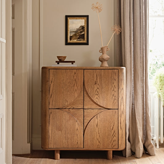 Wooden Oak two door cabinet in a room with a painting and vase on top