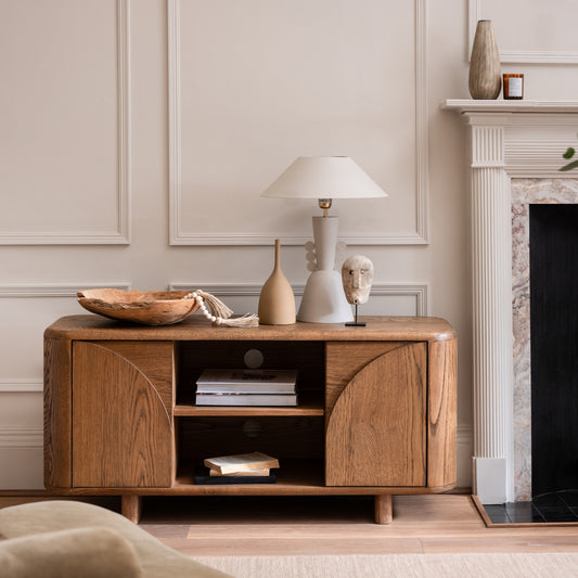 Oak tv unit in living room setting with a lamp and decorative objects on top 