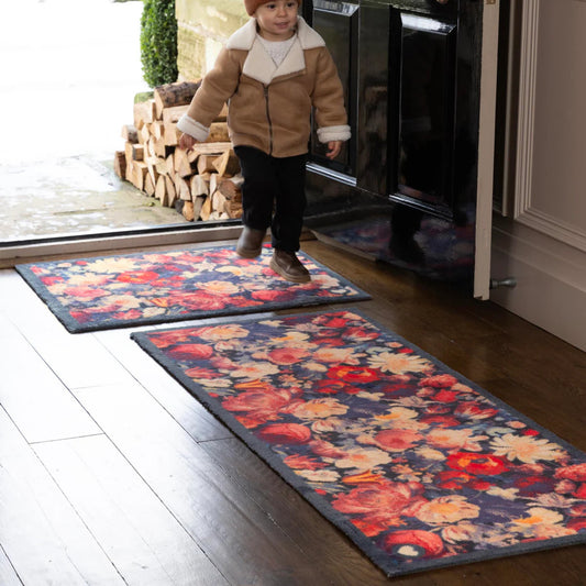 Child standing on a floral-patterned rug in a home setting
