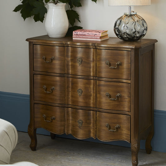 walnut 3 drawer chest with a lamp, books and vase sitting on top in a bedroom setting 