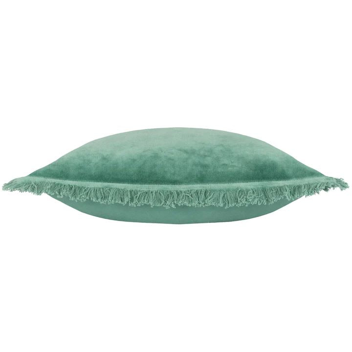 A teal green velvet cushion with fringed edges side view