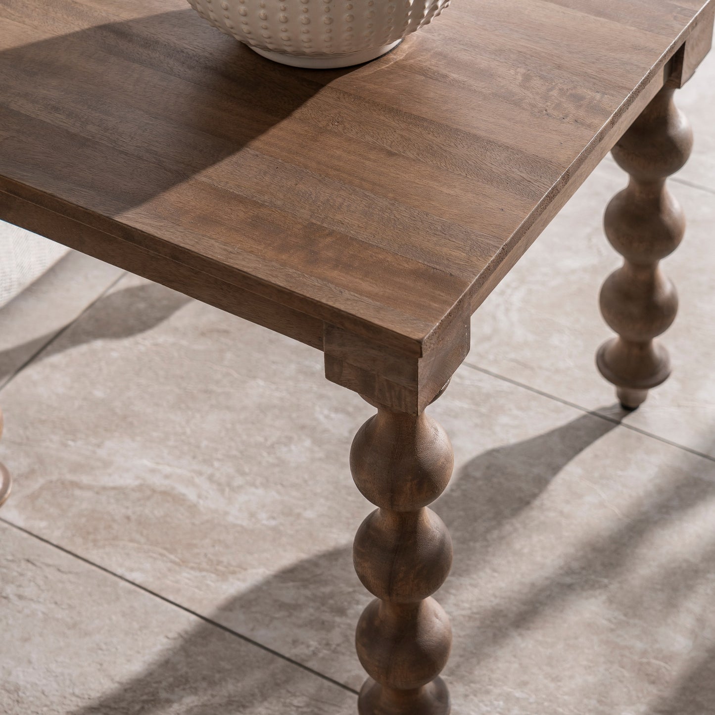 Wooden table with turned legs on a tiled floor