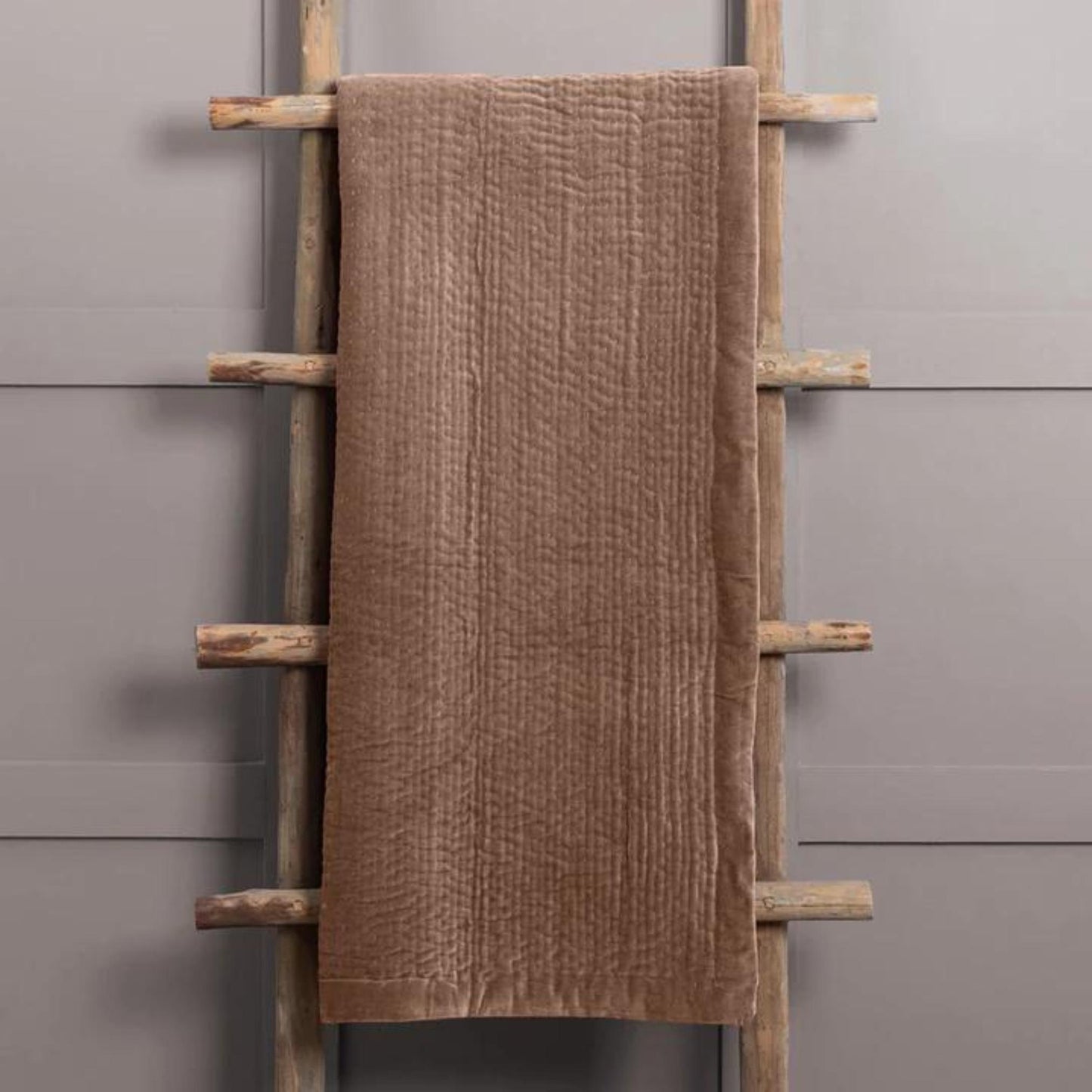 Dusky Pink velvet Throw hanging on a wooden ladder set against a grey wall 