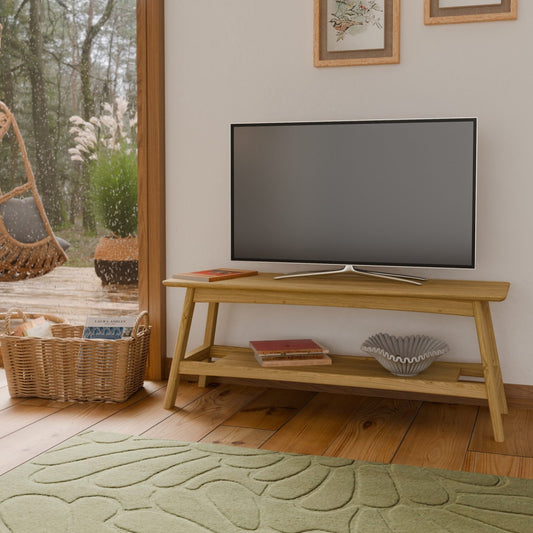 Wooden TV stand with a television in a room with a window view of trees.
