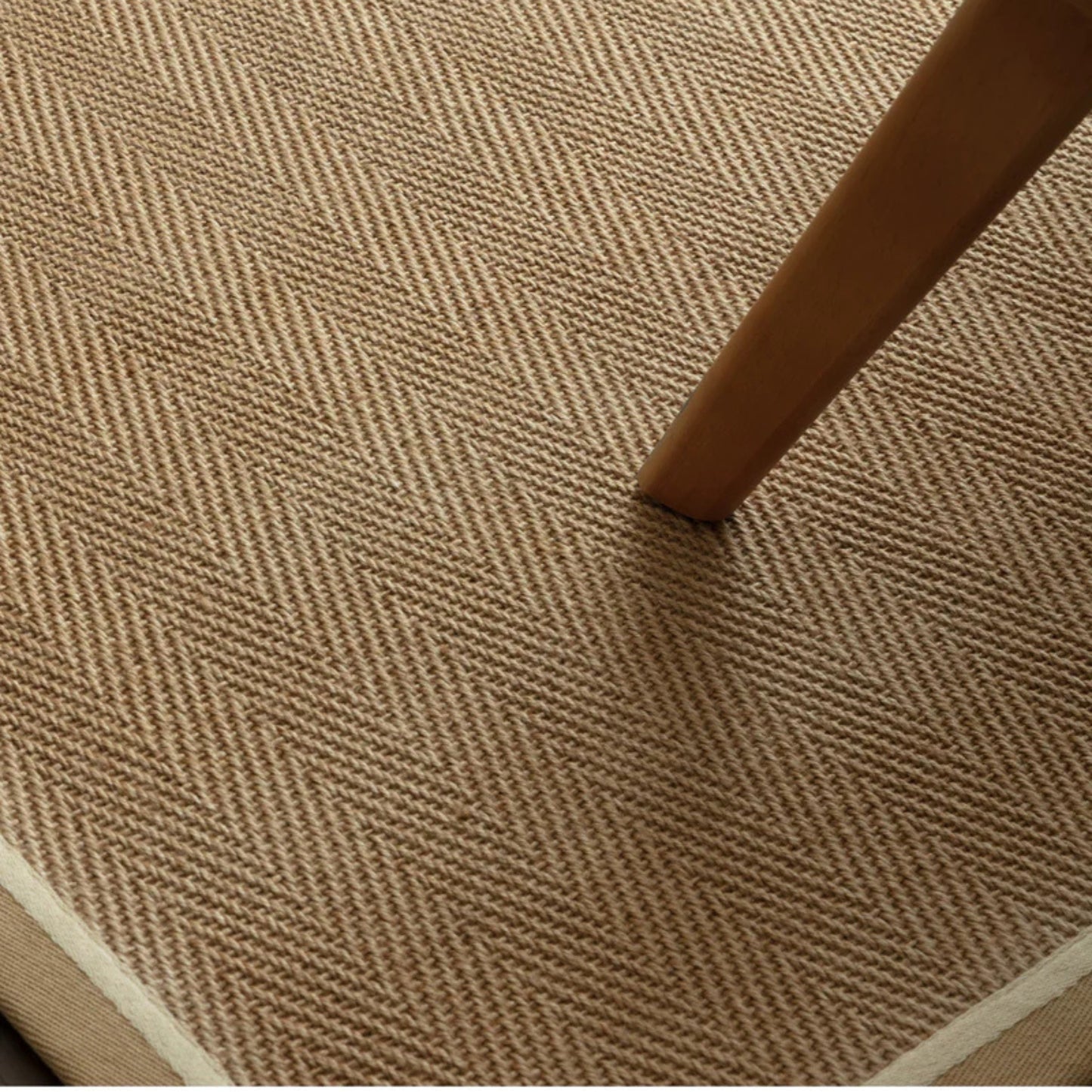 Close-up of a textured brown carpet with a wooden chair leg.