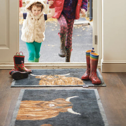 Kids entering a house with wellies on highland cow door mats