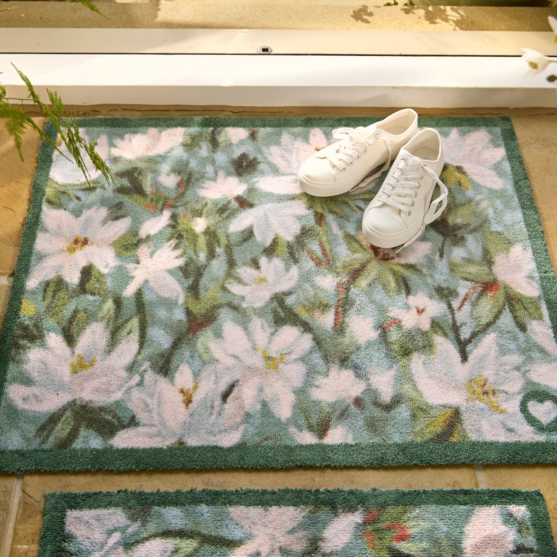 Hug Rug Water Lily Green Toned Floral Design Door Mat with White Sport Shoes at doorway entrance