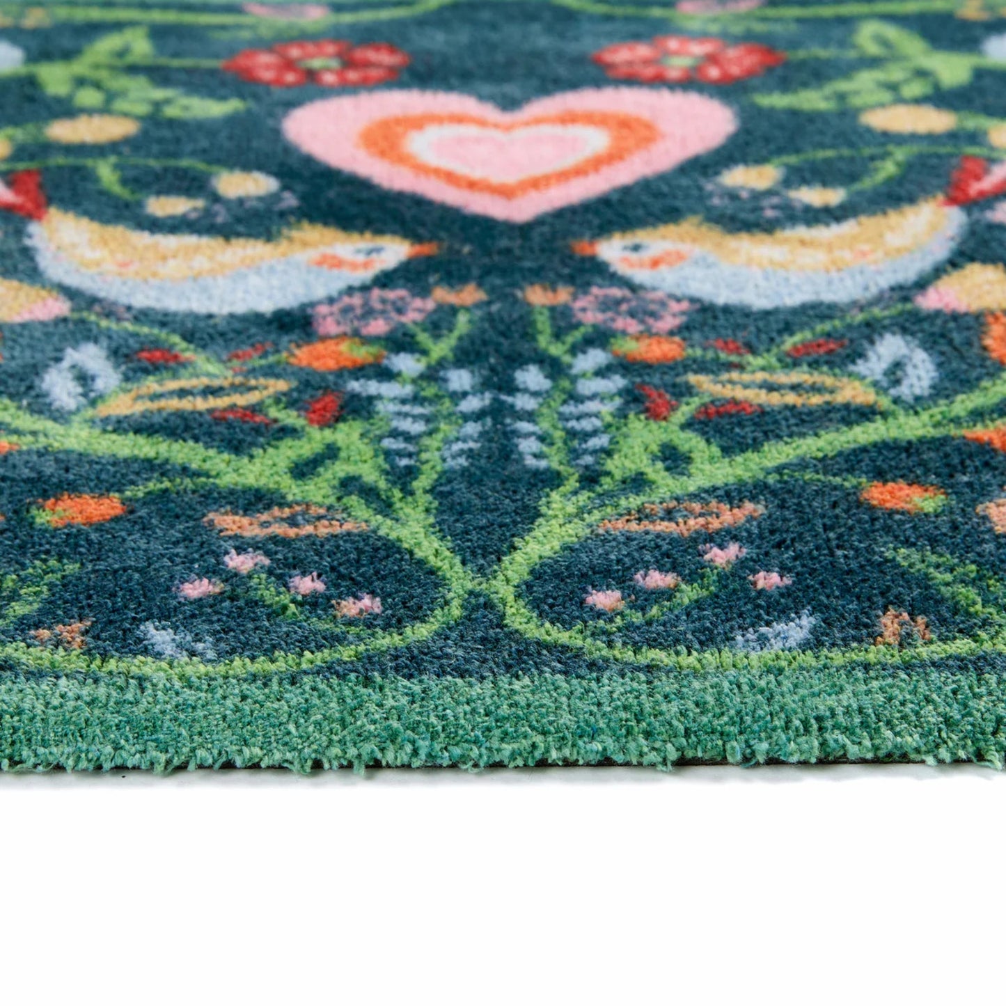 close up of rug pattern detail showing two birds and a heart on a blue background