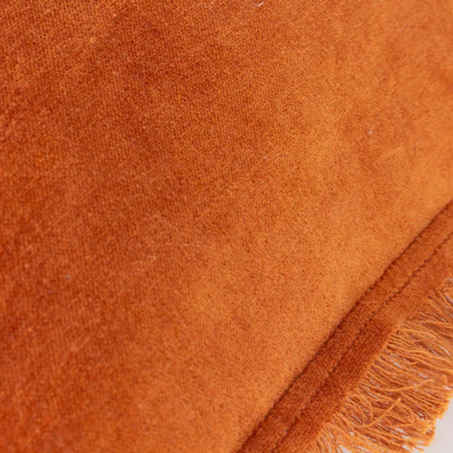 Close-up of orange velvet fabric with frayed edge