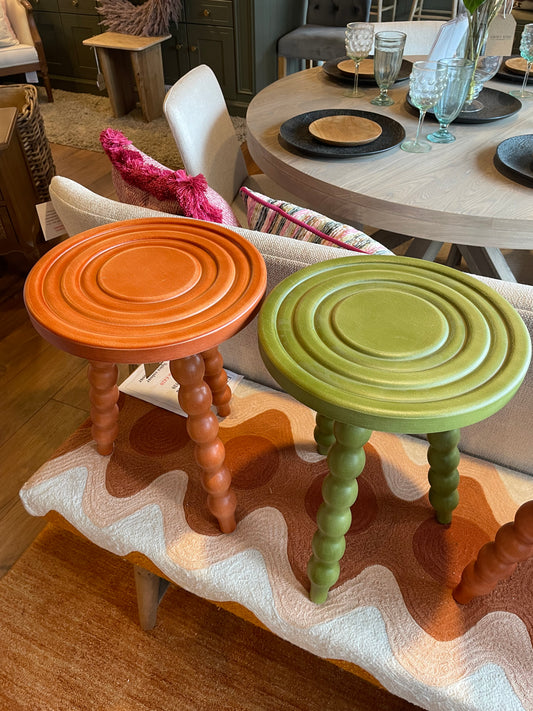 Colorful wooden stools on a textured surface with a blurred background
