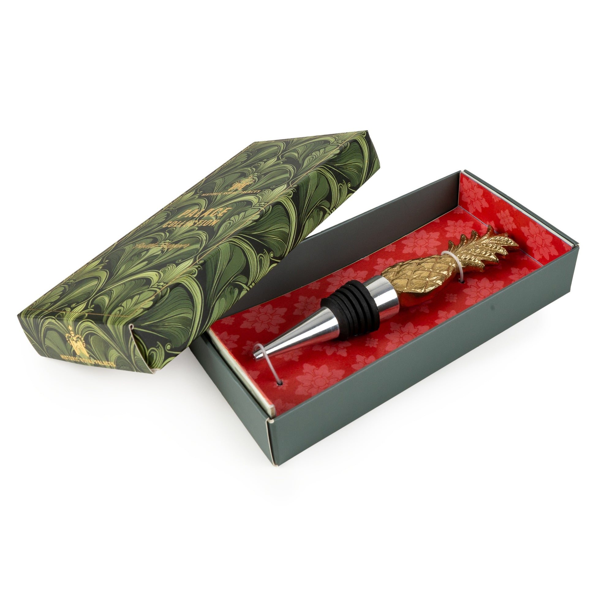 Decorative bottle stopper with gold pineapple design in a green marbled box on a white background