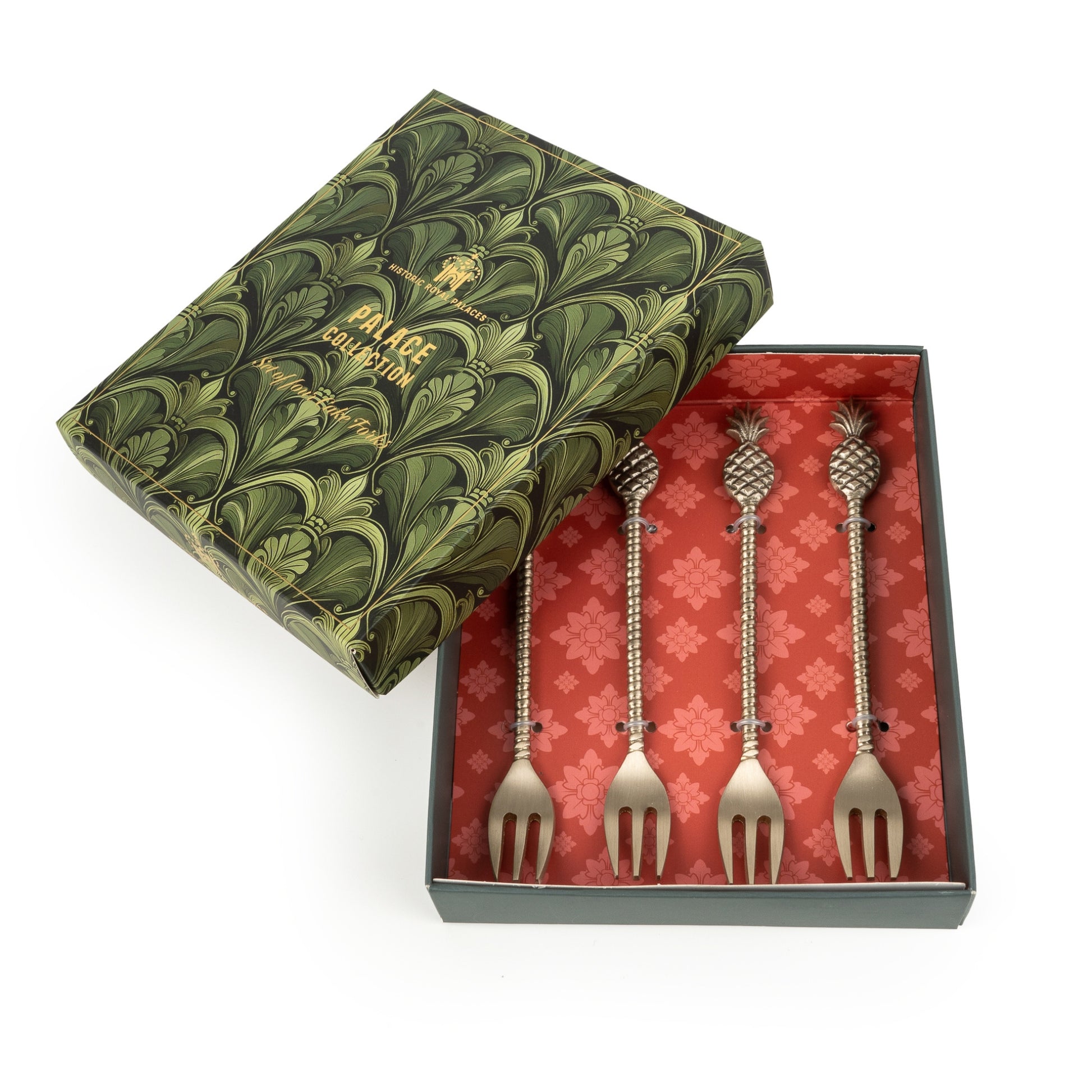 Set of four silver forks in a decorative box with a green lid and red interior.