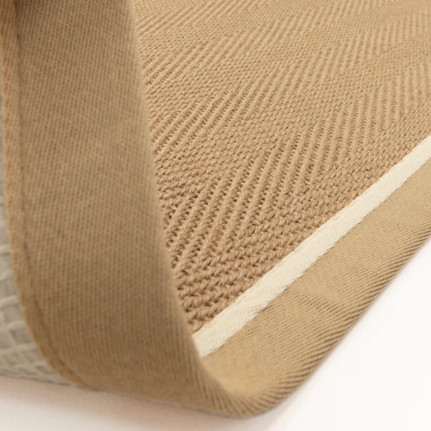 Close-up of a textured beige rug with a white border on a light background