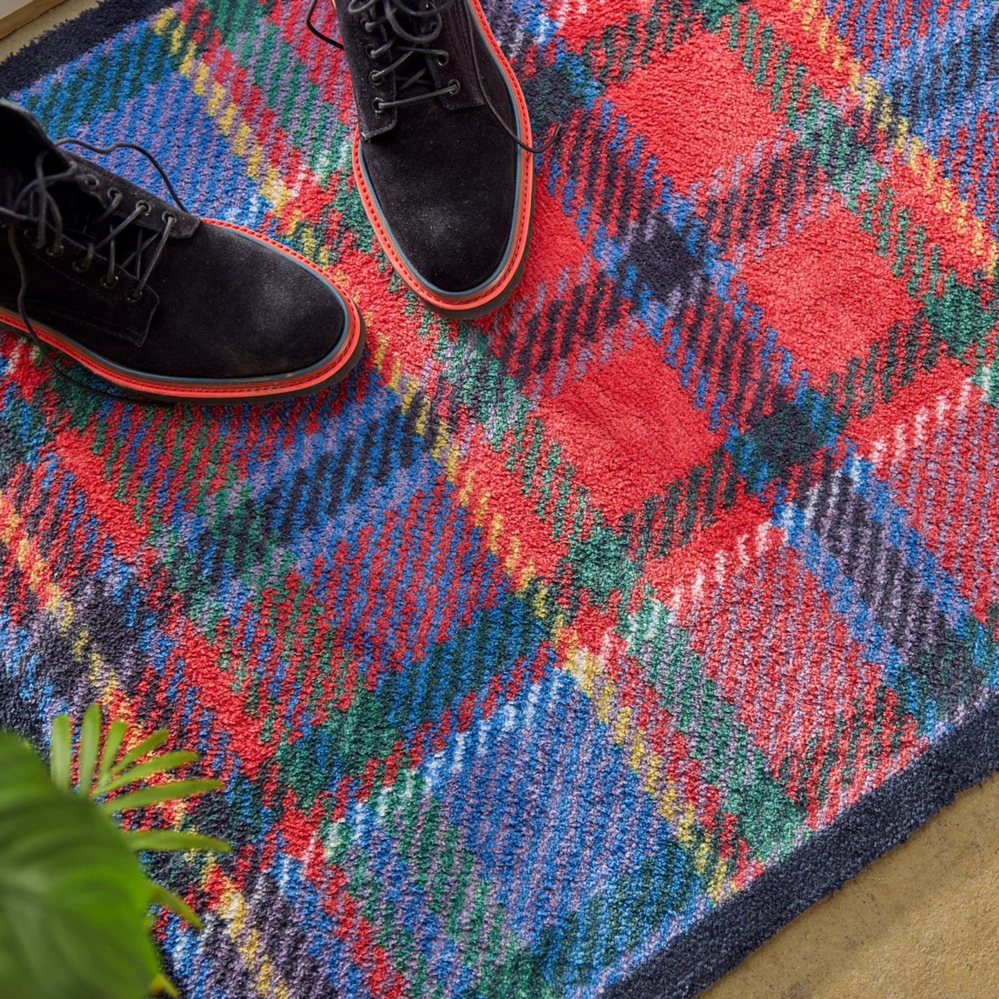 Close up of tartan door mat with black boots 