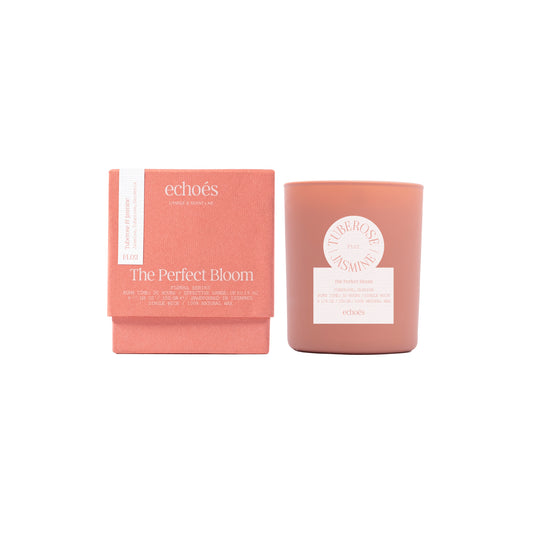 A tumbler candle with a pink label reading 'Echoes' and 'The Perfect Bloom' alongside a matching pink box.